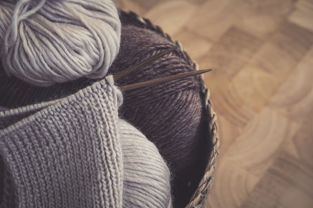 Pelotes de laine dans un panier avec un tricot en cours sur aiguilles