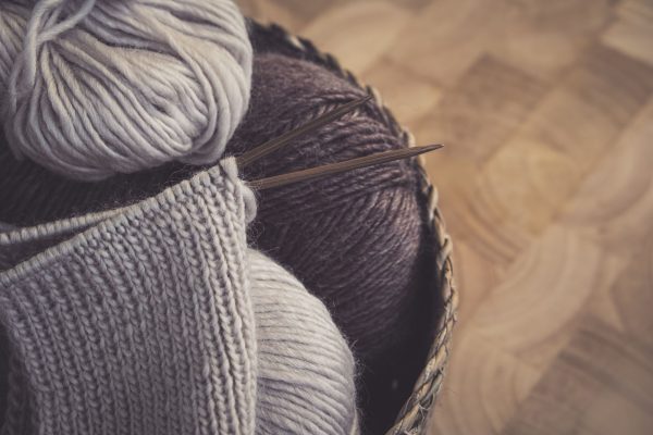 Pelotes de laine dans un panier avec un tricot en cours sur aiguilles