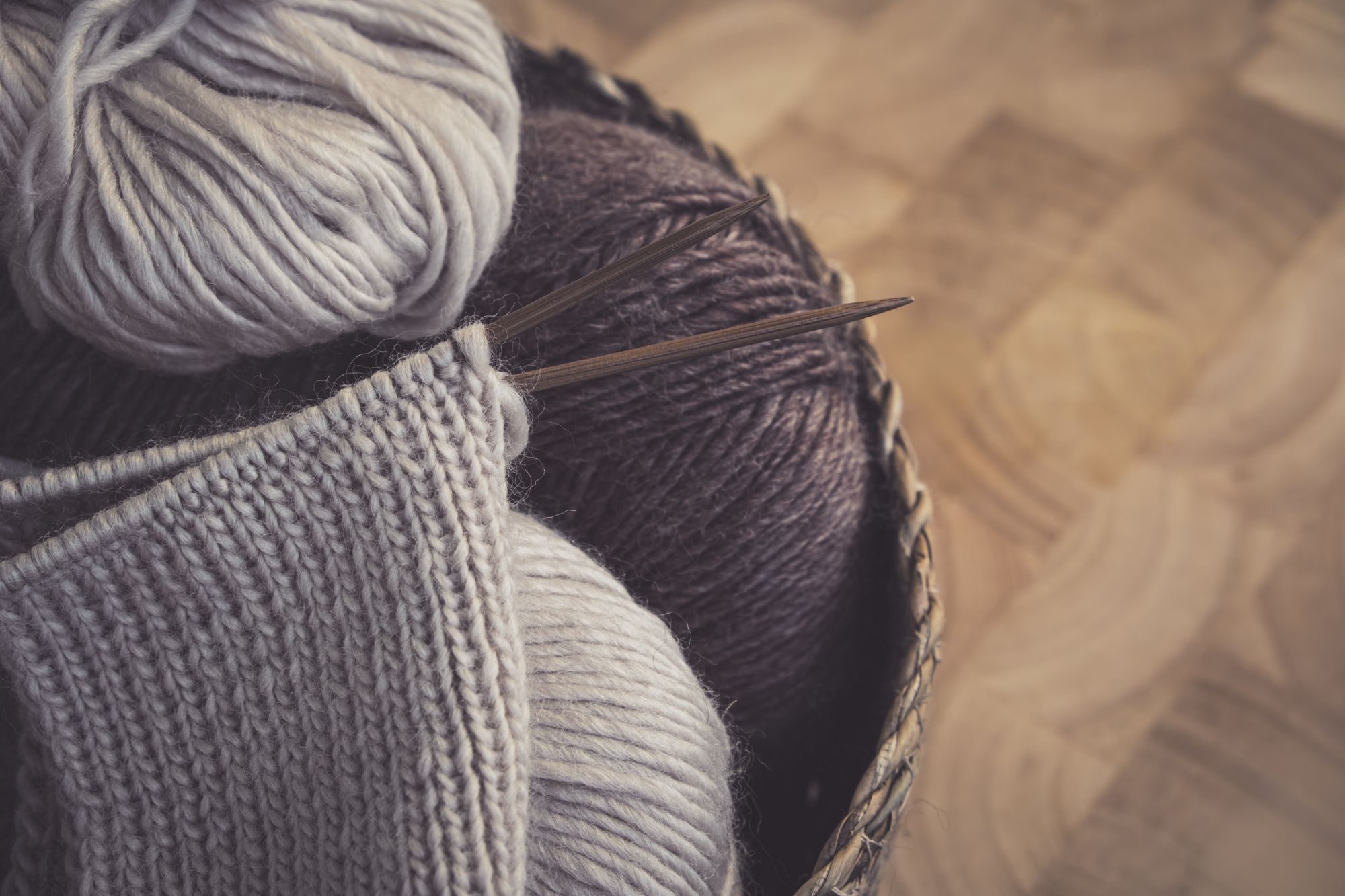 Pelotes de laine dans un panier avec un tricot en cours sur aiguilles